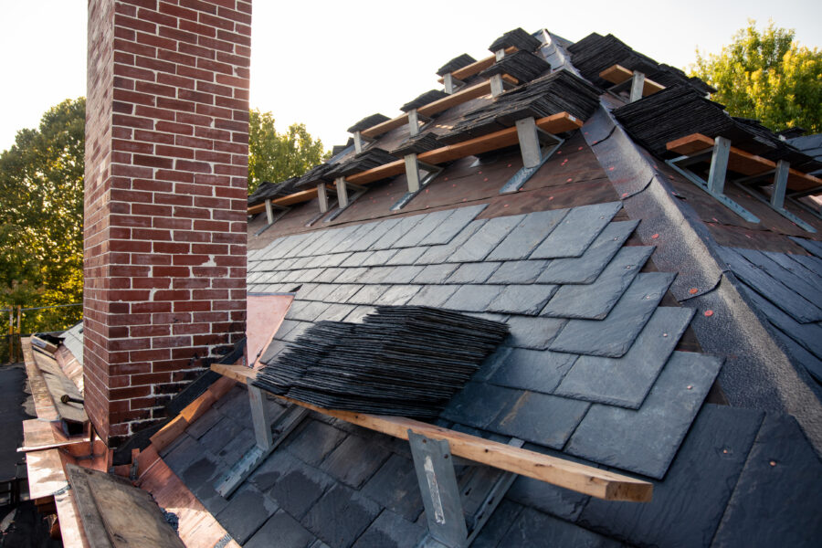 Slate roof installation in progress showing piles of slate shingles ready to be installed