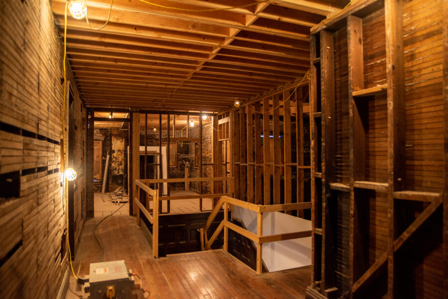 Interior restoration on the 2nd floor of the Schifferdecker home, showing exposed wall and ceiling studs and temporary banisters in a hallway