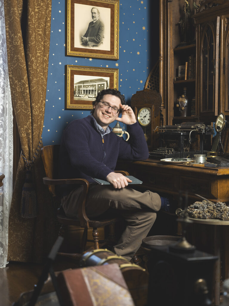 Zackary Brower sitting at an antique desk with Victorian era office props